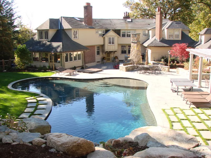 Belmont pool landscape with stone patio, lawn, and outdoor living areas
